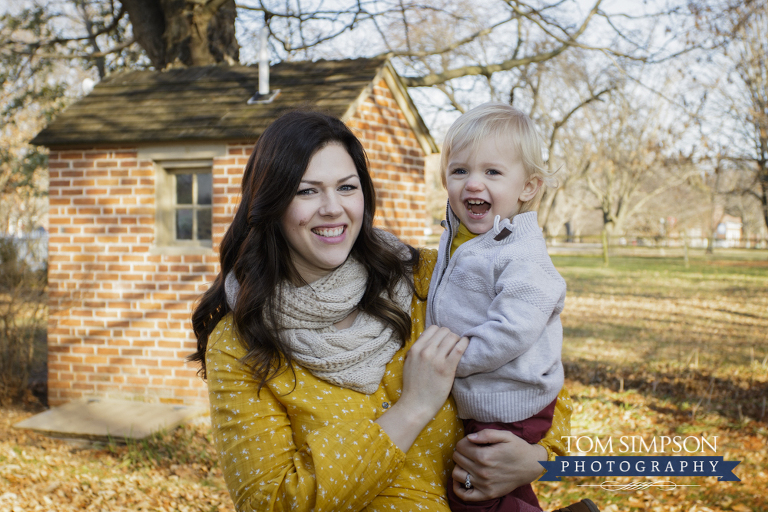 mother laughing baby outdoor portrait red brick