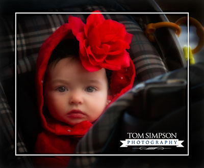 baby with bright red flower on her head